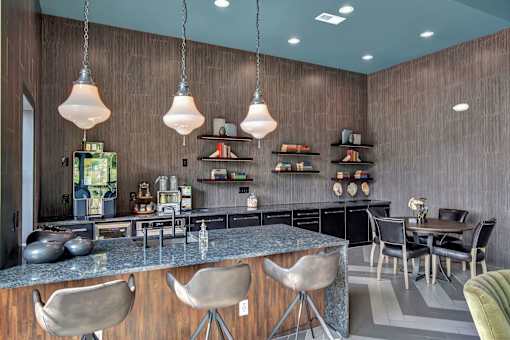Clubhouse kitchen and bar with large island seating, pendant lights, and open shelving.