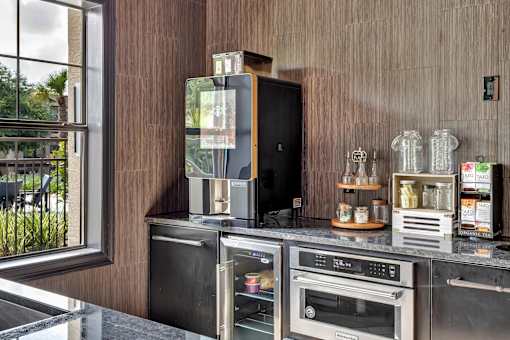 Refreshment station with countertop appliances, storage cabinetry, and tea display.