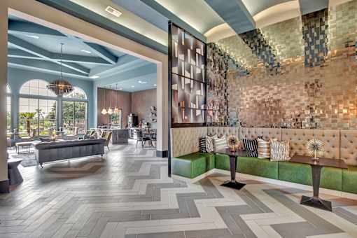 Clubhouse lounge with tufted banquette seating, modern tile floors, and open layout.