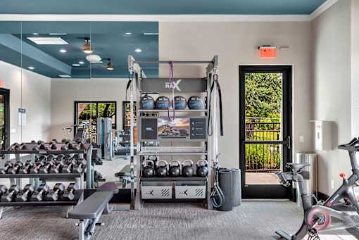 Functional training station with kettlebells, dumbbells, and mirrored wall in gym.