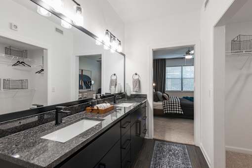 Bathroom with double-sink vanity, granite countertop, and walk-in closet access.
