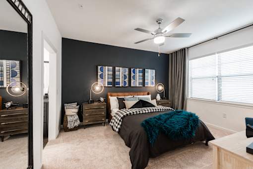 Bedroom view with nightstands, modern lighting, and soft carpet under a ceiling fan.