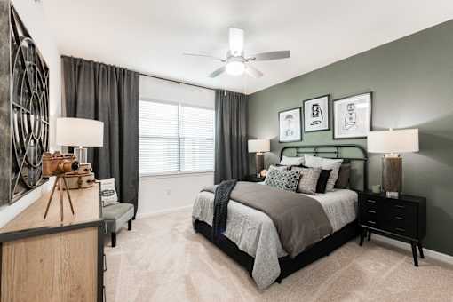 Cozy bedroom with ceiling fan, bedside lighting, and a green accent wall.