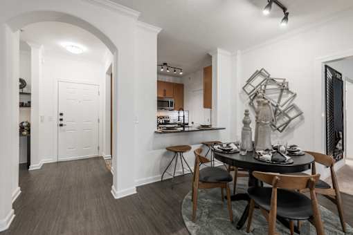 Dining nook with arched entryway and kitchen bar seating in an open floor plan.