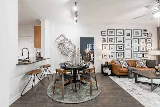 Round dining table set beside a pass-through counter, with living room seating nearby.