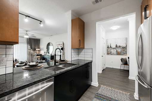 Modern kitchen with black cabinetry and granite counters, opening to the main living area.
