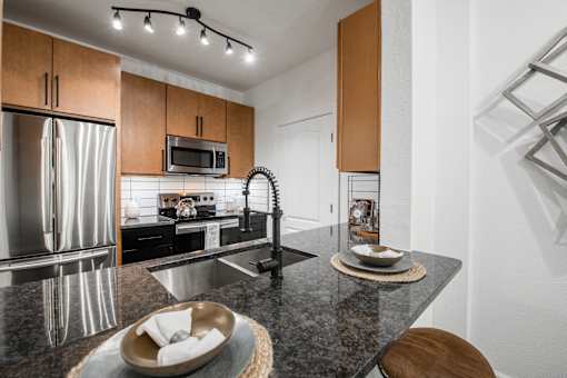 Kitchen island with granite countertop, undermount sink, and stainless steel appliances.