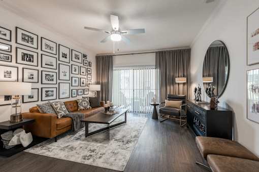Parkview Terraces living room with leather sofa, gallery wall, and sliding patio doors.