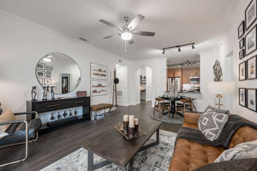 Open living and dining area with ceiling fan, wood-style floors, and breakfast bar.
