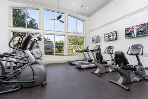A gym with a row of stationary bikes and a fan.