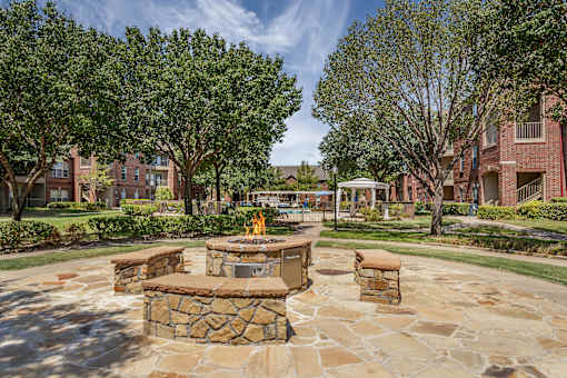 A stone fire pit sits in the middle of a courtyard.