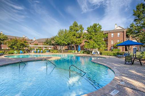 A swimming pool with a blue umbrella and a building in the background.