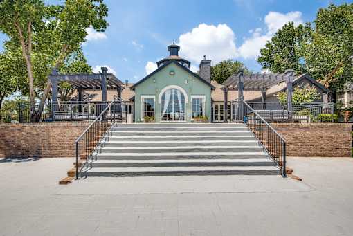 A green building with a black roof and a set of stairs leading up to it.