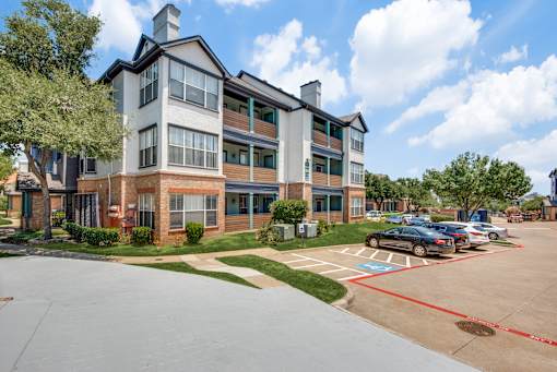 A large apartment complex with a parking lot in front.