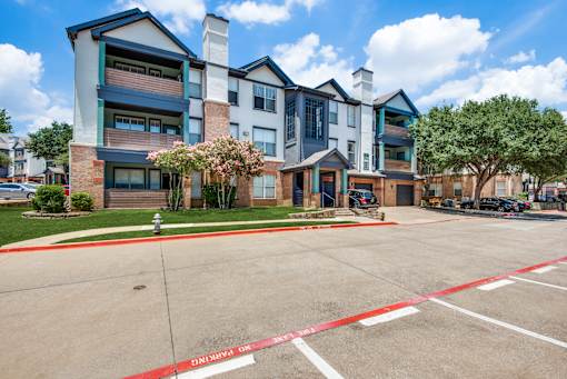 A large apartment complex with a red and white striped barrier in front.