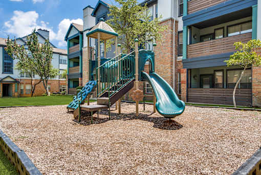 A playground with a green slide and a wooden structure.