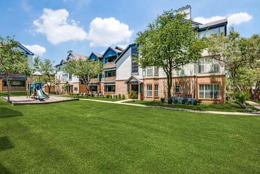 A large grassy area in front of a building with a playground.