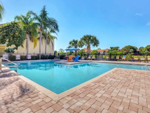 a resort style swimming pool with chaise lounge chairs and palm trees