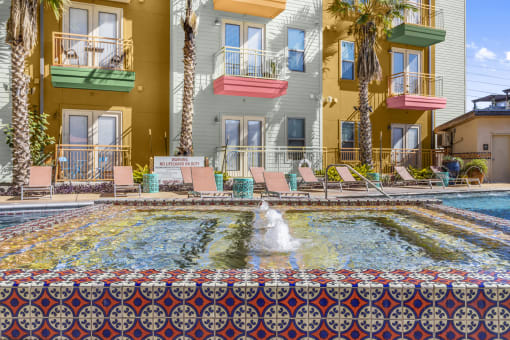a pool with a fountain in front of a building