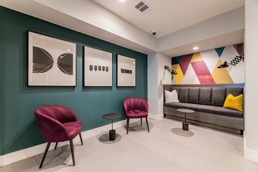 A seating area with a grey sofa, two red chairs and a small table.