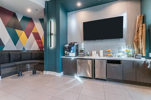 A modern common area kitchen with a black countertop and a television.