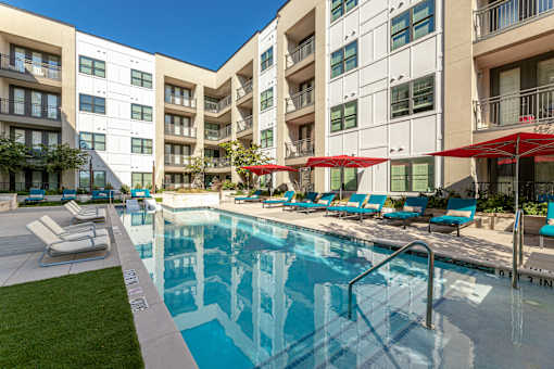 A swimming pool with lounge chairs and umbrellas.