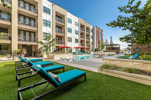 A row of sun loungers are on a lawn in a courtyard.