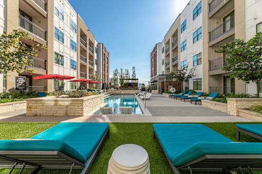 A swimming pool surrounded by a grassy area and lounge chairs.