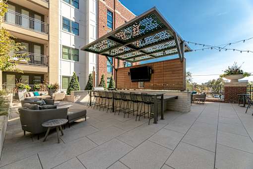 An outdoor seating space with a larger counter and chairs.