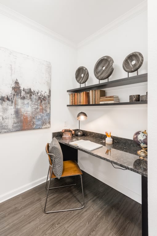 a desk with a chair and a lamp in a room with a painting on the wall
