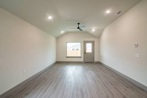 A room with a ceiling fan and a door leading to a balcony.