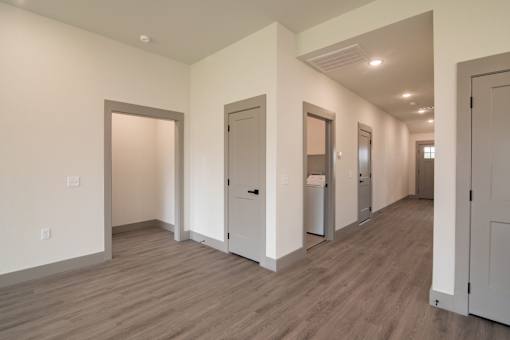 A long hallway with white walls and wood floors.