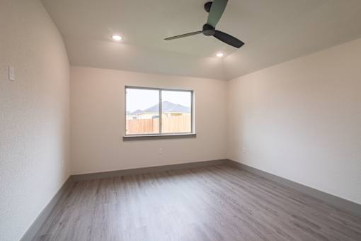 Empty room with a window and a ceiling fan.