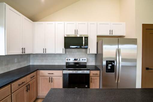 A kitchen with black countertops and stainless steel appliances.