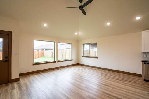 A room with a ceiling fan and two windows.