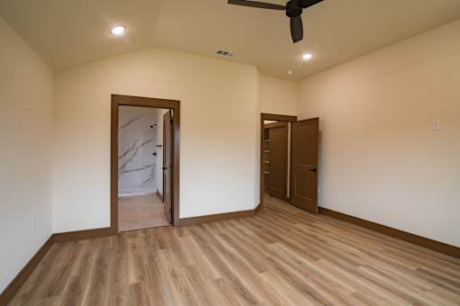 A room with a ceiling fan and wooden flooring.