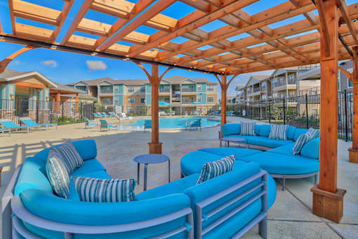 A wooden pergola over a blue seating area.