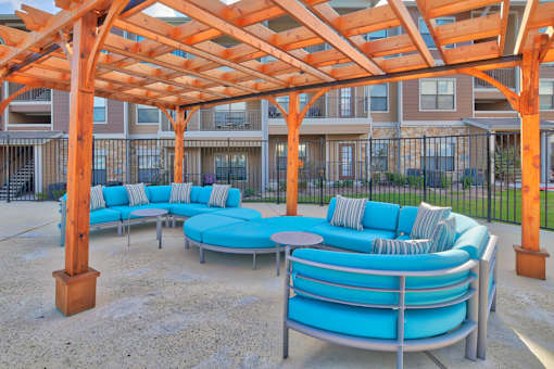 A patio with a blue couch and a wooden pergola.
