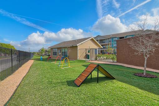 A playground with a slide and a tree in a grassy area.