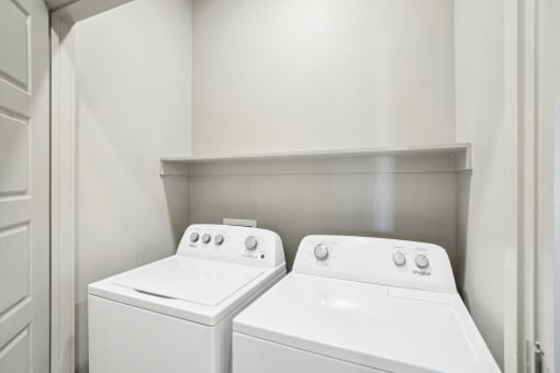 the laundry room of a home with two washes and a dryer