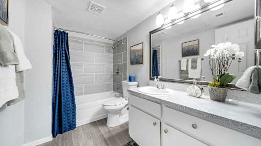 a white bathroom with a blue shower curtain and a toilet