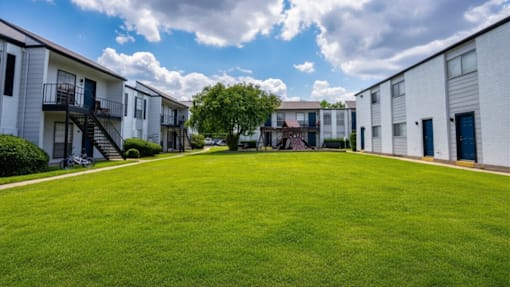 A grassy area in front of apartment buildings.