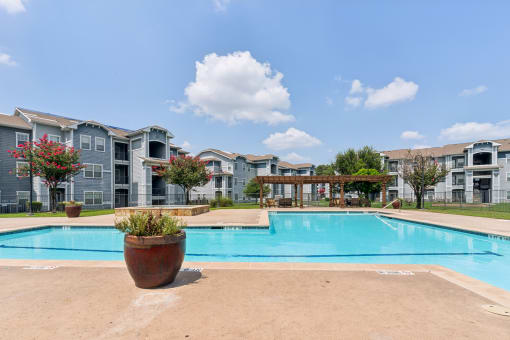 a large swimming pool with apartments in the background