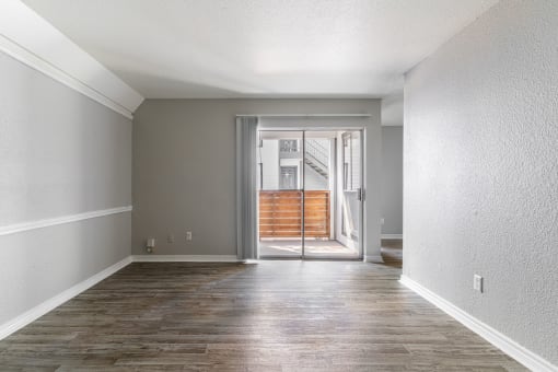 an empty living room with a sliding glass door to a patio