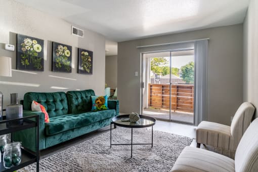 a living room with a green couch and a sliding glass door