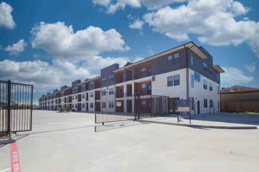 Gated apartment community entrance with modern townhomes at The Aurea Apartments, Houston