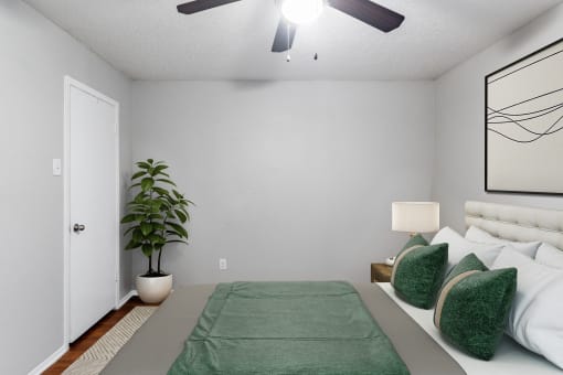 a bedroom with a bed and a plant and a ceiling fan
