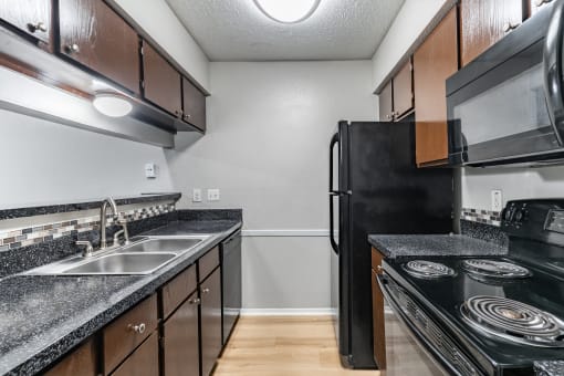 the kitchen of our studio apartment atrium with black appliances and granite countertops