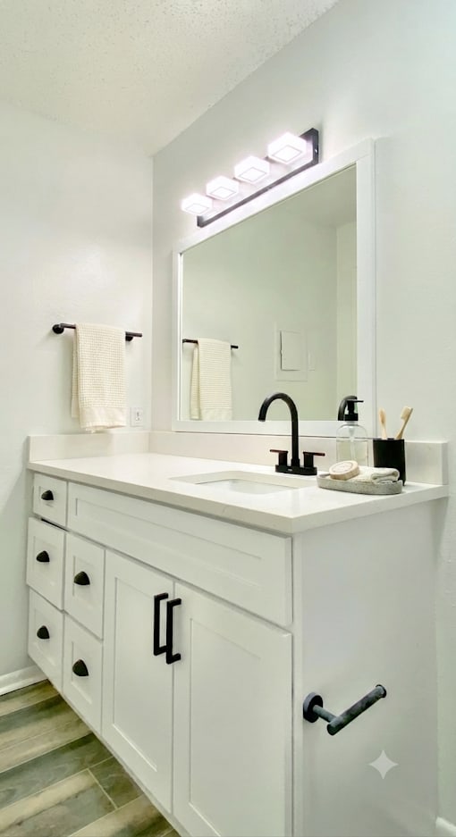 A white bathroom vanity with a mirror and lights above it.