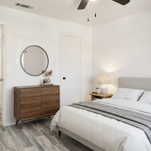 A bedroom with a bed, dresser, and mirror.
